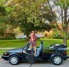 a woman standing on the open door of a car