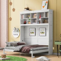 a white bed sitting under a book shelf next to a green table and chair in a room