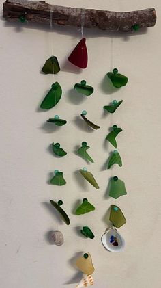 a wind chime hanging from a tree branch with sea glass and seashells