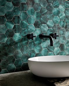 a white bowl sink sitting on top of a counter next to a green tiled wall