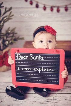 a baby is holding up a sign that says dear santa i can explan