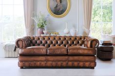 a living room filled with furniture and a painting on the wall above it's windows