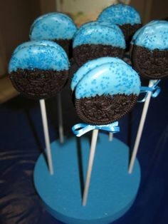 chocolate cake pops with blue frosting and brown sprinkles on top are arranged in a cupcake holder