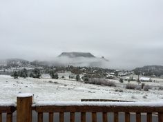 a snowy landscape with mountains in the distance and trees on the other side as seen from a deck