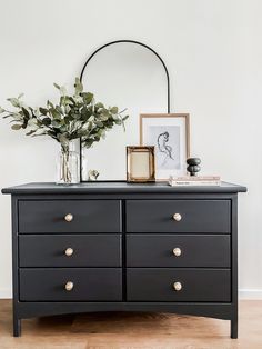 a black dresser with gold handles and brass knobs in front of a white wall