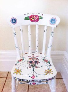 a white wooden chair with floral designs painted on it