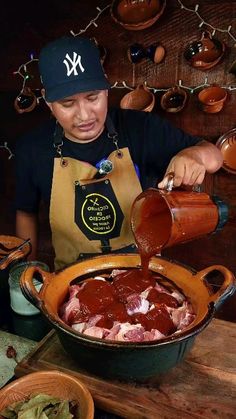 a woman pouring sauce into a pot filled with meat