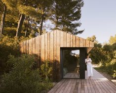 a woman standing on a wooden deck in front of a building with a door open