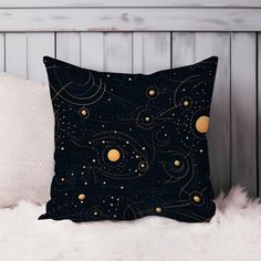 a black pillow with gold stars and planets on it