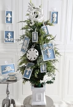 a small christmas tree decorated with blue and white ornaments on top of a round table