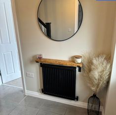 a round mirror hanging on the wall above a radiator