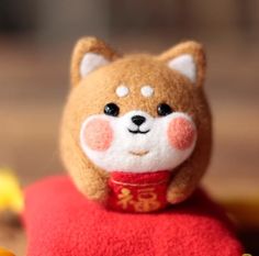 a small stuffed animal sitting on top of a red pillow with chinese writing in it