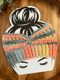 a crocheted headband with a bow on it sitting on top of a wooden table