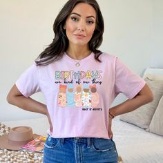 a woman standing in front of a bed wearing a pink shirt with the words birthdays on it