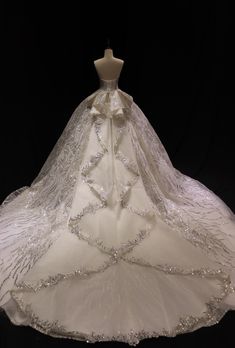 a white wedding dress on display in front of a black background