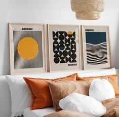 three art prints hanging on the wall above a bed with pillows and blankets in front of them