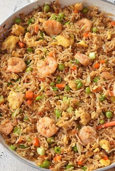 a pan filled with shrimp and rice on top of a table