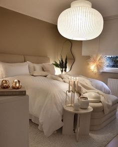 a white bed sitting in a bedroom next to a lamp on a table and chair