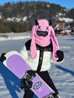 a snowboarder wearing a pink bunny hat and holding a purple snowboard in the snow