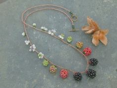 a necklace with beads and flowers on it sitting next to a flower potted plant