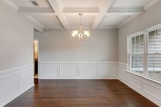 an empty living room with wood floors and white paint on the walls, along with a chandelier