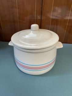 a white casserole with blue and pink stripes on the bottom is sitting on a table