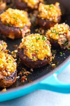 cooked stuffed mushrooms with cheese and seasoning in a blue skillet on a table