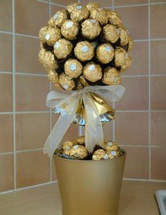 a gold vase filled with chocolates and wrapped in ribbon on top of a counter