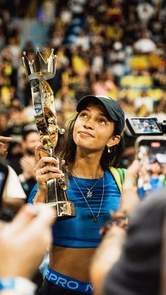 a woman holding up a trophy in front of a crowd