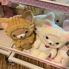 several stuffed animals are on display in a toy store's shelf, one is brown and the other is white