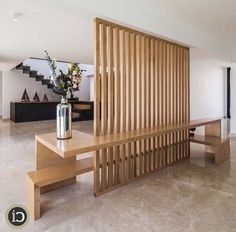 a wooden bench sitting in the middle of a room next to a vase with flowers