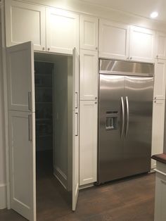 a stainless steel refrigerator and freezer in a kitchen with white cabinets, wood flooring