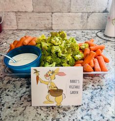 a bowl of carrots and broccoli next to a card