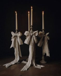 three candles with bows on them are lit in the dark by some kind of candle holder