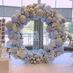 a white table topped with balloons and a wreath on top of it's head