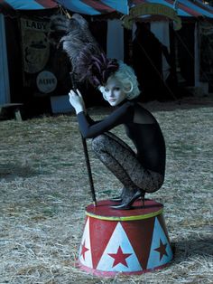 a woman sitting on top of a red and white circus tent with words above her