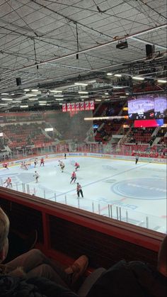 an ice hockey game is being played in a large arena with people sitting on the seats watching