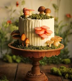 a cake with mushrooms on it sitting on top of a wooden table next to plants