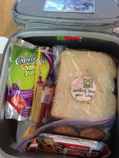 an open lunch box with sandwich, candy and snacks