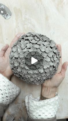 two hands holding a round object made out of silver coins and another person's hand reaching for it