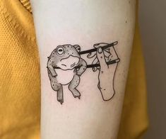 a frog is hanging on to a clothes line with a person's leg in the background