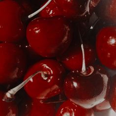 red cherries are piled on top of each other with silver spoons in them