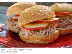 two sandwiches with apple slices and meat are on a red plate, ready to be eaten