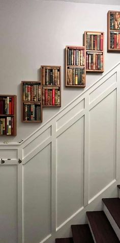 the books are lined up on the wall next to the stairs