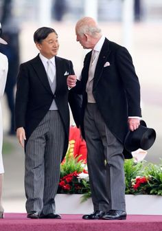 two men standing next to each other in suits