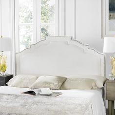 a white bed sitting in a bedroom next to two lamps on either side of it