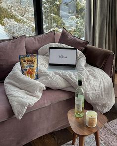 an open laptop computer sitting on top of a couch next to a bottle of wine