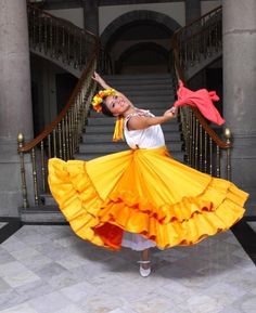 a woman in an orange and yellow dress is dancing