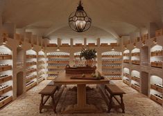 a room filled with lots of wine bottles and wooden benches next to a light fixture