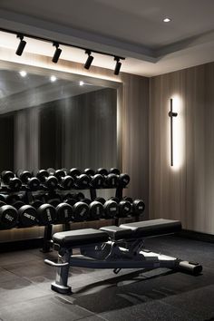 an empty gym with rows of dumbs and benches in front of a cross - shaped mirror